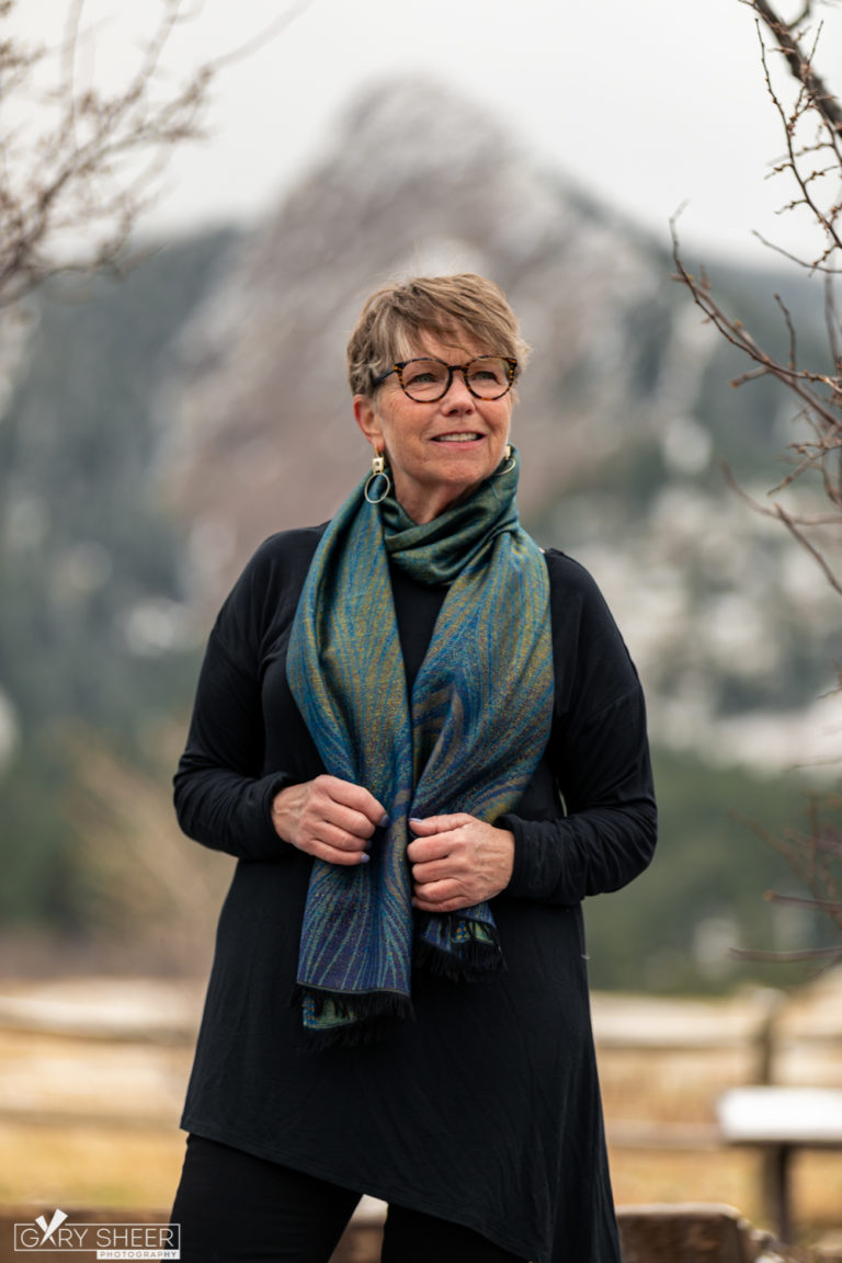 Portrait of woman in glasses wearing a scarf outside with a mountain blurred in the background © Gary Sheer Photography