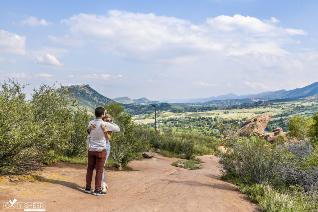 couple at the top of a mountain in Denver hugging in engagement photo session